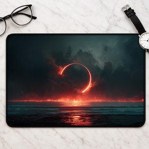 May include: A rectangular mousepad featuring a dramatic landscape with a fiery red ring in the sky, above a dark ocean. The scene is set against a backdrop of ominous clouds, creating a striking contrast. The mousepad has a black border.