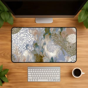 May include: A rectangular mouse pad with a floral design in shades of white, blue, and brown. The pattern includes large, stylized flower shapes and a marbled background. The pad is on a wooden desk with a keyboard and coffee cup.