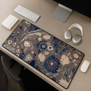 Könnte beinhalten: Eine rechteckige Schreibtischunterlage mit dunkelbraunem Hintergrund und einem sich wiederholenden Muster aus stilisierten Blumen in Marineblau, Creme und Hellbeige. Die Unterlage hat einen schwarzen genähten Rand und eine glatte Oberfläche.