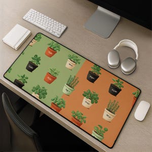 May include: A rectangular desk mat featuring a split-colour background of sage green and terracotta orange. The surface is covered in a repeating pattern of various potted herbs, including basil and rosemary, in black, white, and terracotta pots.