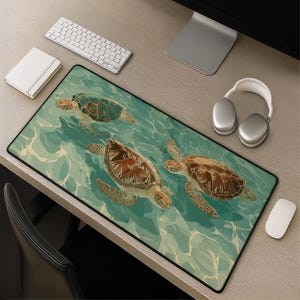 May include: A rectangular desk mat featuring an illustration of three sea turtles swimming in turquoise water. The turtles have brown and green shells. A white keyboard, mouse, and headphones are also visible on the desk.