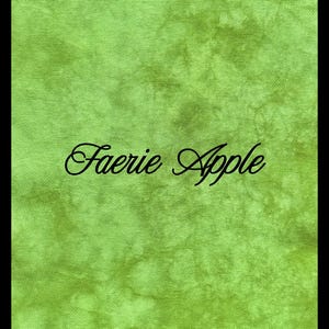 May include: A rectangular piece of fabric featuring a mottled, variegated light and medium green color pattern. The text Faerie Apple is printed in a black, cursive, script-style font across the center of the green textured material.