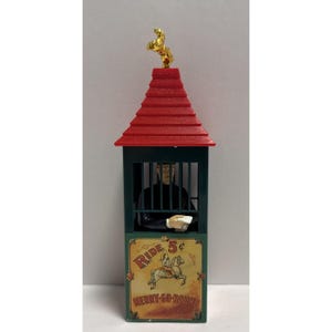 May include: A ticket booth model with a red tiered roof topped by a gold horse figure. The dark green structure features a figure inside a barred window and a sign reading Ride 5 cents Merry-Go-Round with a horse illustration.
