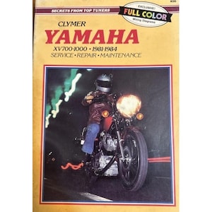 May include: A vintage Clymer repair manual for Yamaha XV700-1000 motorcycles from 1981-1984. The cover features a motorcycle with a rider and the text "YAMAHA" in large red letters. The manual includes full-color wiring diagrams.