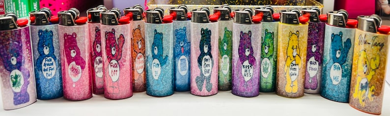 Puede incluir: Una colecci&oacute;n de encendedores cubiertos de purpurina con dise&ntilde;os de Ositos Cari&ntilde;ositos. Cada encendedor tiene un oso diferente y una frase &uacute;nica. Los encendedores son de varios colores, incluyendo azul, rosa, morado y amarillo.