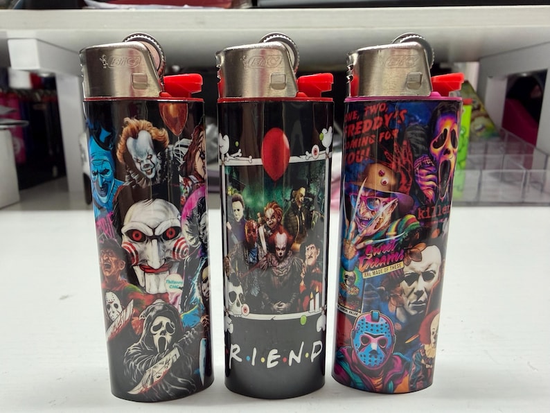 Peut inclure: Trois briquets cylindriques arborant des impressions graphiques color&eacute;es de divers personnages de films d'horreur. Les motifs incluent des figures embl&eacute;matiques comme Pennywise, Billy the Puppet, Ghostface, Freddy Krueger et Jason Voorhees, avec le texte R.I.E.N.D.S.