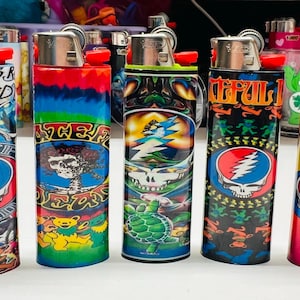 Puede incluir: Una colecci&oacute;n de encendedores recargables con dise&ntilde;os coloridos. Los encendedores presentan varios gr&aacute;ficos, incluido el logotipo Steal Your Face de Grateful Dead, osos y patrones psicod&eacute;licos. Los encendedores son cil&iacute;ndricos y tienen una parte superior de metal con un bot&oacute;n de encendido rojo.