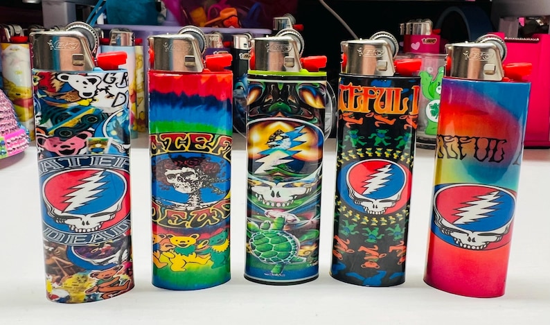 Puede incluir: Una colecci&oacute;n de encendedores recargables con dise&ntilde;os coloridos. Los encendedores presentan varios gr&aacute;ficos, incluido el logotipo Steal Your Face de Grateful Dead, osos y patrones psicod&eacute;licos. Los encendedores son cil&iacute;ndricos y tienen una parte superior de metal con un bot&oacute;n de encendido rojo.
