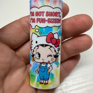 May include: A Bic lighter featuring a tie-dye background and a graphic of a character wearing a cat-ear headband with a red bow. Above the character is a speech bubble containing the text, I'M NOT SHORT, I'M FUN-SIZED! in red capital letters.