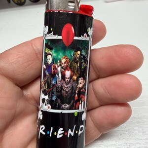 Peut inclure: Un briquet Bic noir orn&eacute; d'une impression graphique repr&eacute;sentant divers personnages de films d'horreur, un ballon rouge et un cr&acirc;ne. Le texte R.I.E.N.D est imprim&eacute; en blanc en bas, avec des points color&eacute;s entre les lettres. Sommet m&eacute;tallique.