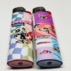 May include: Two lighters with Powerpuff Girls designs. One has a checkered pattern with the text "POWERPUFF GIRLS". The other features a collage of the characters in various poses, set against a purple and pink background.