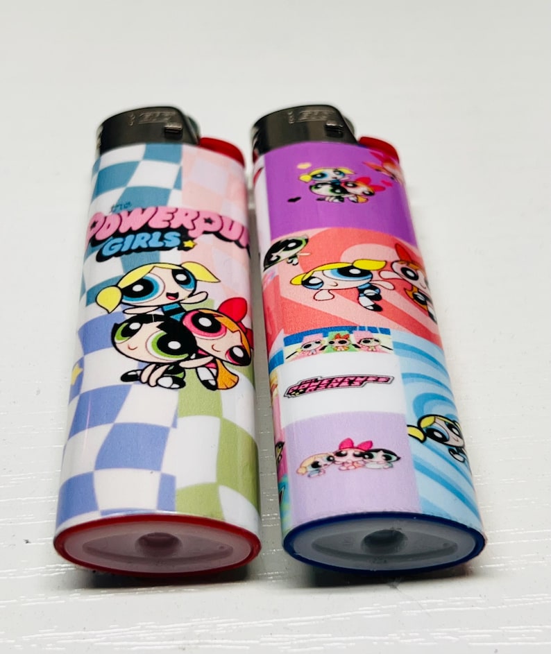 May include: Two lighters with Powerpuff Girls designs. One has a checkered pattern with the text "POWERPUFF GIRLS". The other features a collage of the characters in various poses, set against a purple and pink background.