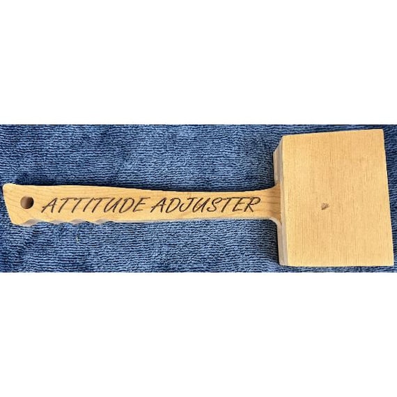 A real wooden mallet laser-engraved with 'Attitude Adjuster' — an actual handmade functional tool that doubles as a deadpan desk trophy.