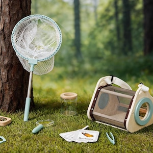 May include: A collection of children's outdoor exploration toys, including a butterfly net, a wooden insect habitat, a compass, a magnifying glass, and a small jar. The items are in shades of green, white, and wood tones, set on a grassy surface.