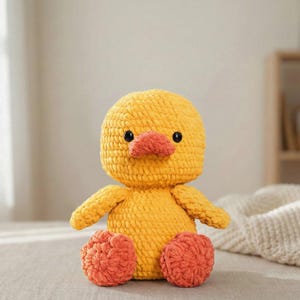 Large amigurumi duck crochet pattern finished sample in soft butter yellow with peach beak and coral feet sitting on a neutral linen backdrop, close up of stitches and shaping to show texture; handmade plush toy photographed to illustrate finished size (about 38 cm tall); pattern PDF includes step-by-step rounds, materials, and assembly photos for beginners and intermediate crocheters.