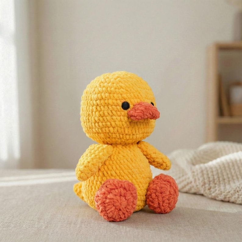 Large amigurumi duck crochet pattern finished sample in soft butter yellow with peach beak and coral feet sitting on a neutral linen backdrop, close up of stitches and shaping to show texture; handmade plush toy photographed to illustrate finished size (about 38 cm tall); pattern PDF includes step-by-step rounds, materials, and assembly photos for beginners and intermediate crocheters.