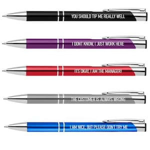 May include: Five ballpoint pens in black, purple, red, gray, and blue. Each pen has silver accents and a different white text inscription: "YOU SHOULD TIP ME REALLY WELL", "I DONT KNOW, I JUST WORK HERE", "ITS OKAY, I AM THE MANAGER!", "THE CUSTOMER IS ALWAYS WRONG", and "I AM NICE, BUT PLEASE DONT TRY ME".