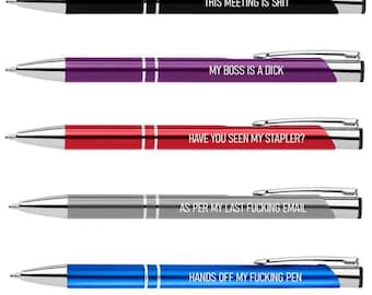 May include: A collection of five ballpoint pens in various colors: black, purple, red, gray, and blue. Each pen has silver accents and a unique, humorous phrase printed on the barrel, including "THIS MEETING IS SHIT" and "MY BOSS IS A DICK."