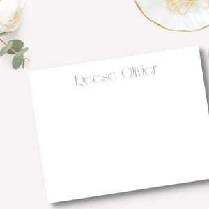 May include: A white card with the name "Reese Oliver" printed in a gray font.