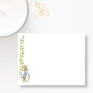 May include: A white card with a green vine border and a watercolor illustration of Peter Rabbit in a blue jacket.