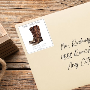 May include: A white envelope with a return address label featuring a pair of brown cowboy boots and the text "THE MILLERS 2020 Any Street Your City, State 55555". The envelope is addressed to "Mr. Rodney 4556 Ranch Any City"