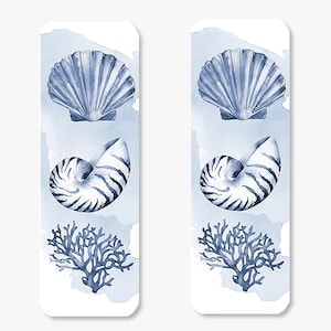 May include: Two rectangular bookmarks with watercolor illustrations of marine life. Each bookmark features a blue seashell, nautilus shell, and coral against a light blue watercolor wash background. The designs are detailed and artistic.