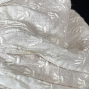 May include: White fabric with a delicate embroidered pattern. The fabric is soft and sheer, with a subtle texture.