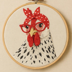 Könnte beinhalten: Gesticktes Reif-Kunstwerk mit einem skurrilen Huhn, das eine rote Brille und ein gepunktetes Stirnband trägt. Das Huhn hat einen roten Kamm und Kehllappen, mit einem schwarz-weiß gefleckten Körper. Das Kunstwerk ist vor einem neutralen Stoffhintergrund.