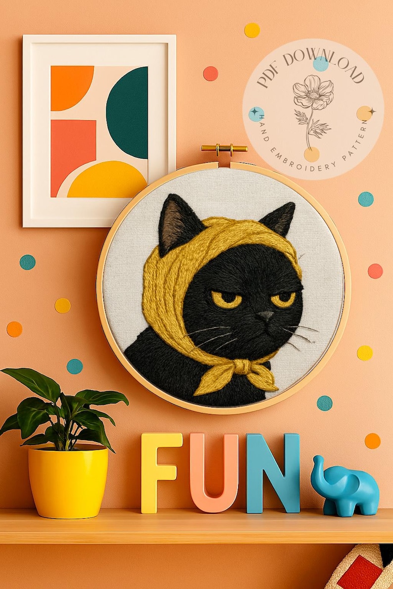 以下が含まれることがあります： 黄色いスカーフをつけた黒猫の刺繍。不機嫌そうな表情と黄色の目。刺繍枠の下にはカラフルな文字で「FUN」と書かれています。抽象的なポスターと鉢植えの植物も表示されています。