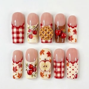 May include: A set of ten press-on nails featuring autumn-themed designs including red and white gingham patterns, painted red apples on branches, a three-dimensional apple pie charm, red maple leaves, a 3D apple slice, and red polka dots.
