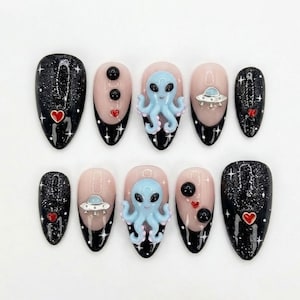 May include: A set of ten press-on nails featuring a space theme. The design includes black glitter nails with white stars and red hearts, alongside nude nails decorated with 3D light blue octopus figures, silver UFO charms, and black spheres.