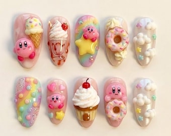 May include: A set of ten press-on nails featuring 3D decorations including pink Kirby characters, ice cream cones, milkshakes, donuts, cupcakes with cherries, rainbows, stars, and white clouds. Each nail has a unique colorful design.