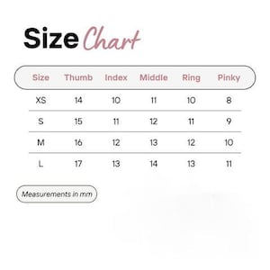 以下が含まれることがあります： 黒とピンクのテキストでSize Chartと書かれたサイズ表。表にはXS、S、M、Lのサイズと、親指、人差し指、中指、薬指、小指に対応する数値が記載されています。下のボックスにはMeasurements in mmと表示されています。