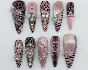 May include: A set of ten almond-shaped press-on nails featuring a pink, black, and silver color palette. The designs include black lace patterns, pink leopard and zebra prints, silver glitter, rhinestones, heart-shaped crystals, and star charms.