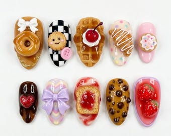May include: A collection of ten artificial nails, each adorned with miniature food-themed decorations. Designs include a donut, cookie, waffle with cherry, croissant, and toast with jam. Other nails feature a heart, bow, and strawberries.