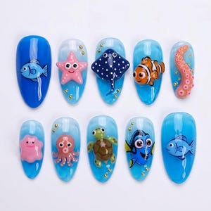 May include: Ten artificial nails with a blue and clear design, featuring sea creatures. Designs include a fish, starfish, stingray, clownfish, octopus, turtle, and Dory from Finding Nemo.