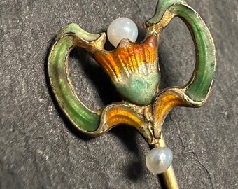 May include: A gold-toned brooch with a green, orange, and yellow enamel flower design. The brooch is accented with two white pearls.