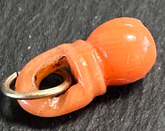 May include: A coral pendant with a gold loop. The coral is a bright orange color and has a smooth, polished finish.