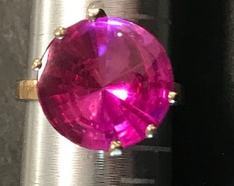 May include: A gold ring with a large, faceted, pink gemstone.