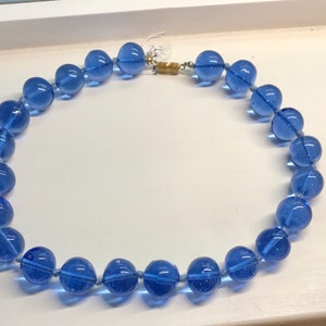 May include: A necklace made of large, round, translucent blue glass beads.