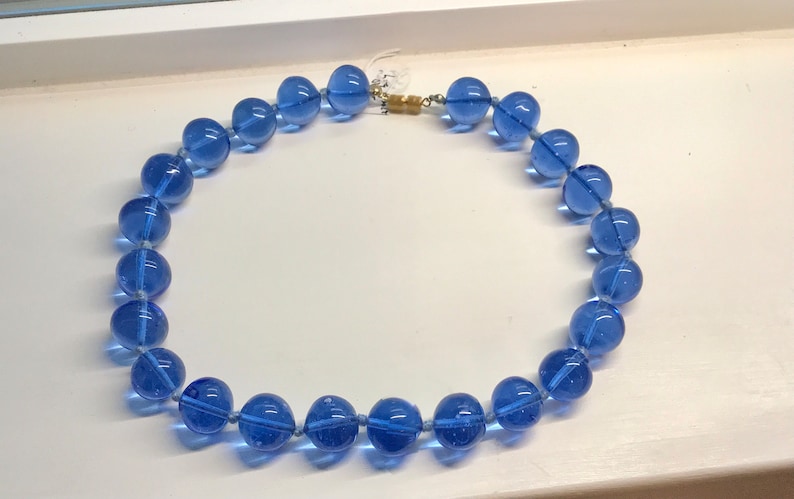 May include: A necklace made of large, round, translucent blue glass beads.