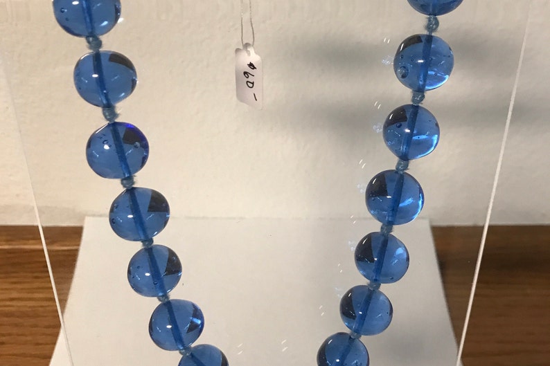 May include: A blue glass bead necklace with a price tag that says "#6D_"