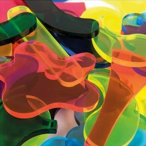 May include: A close-up of a pile of colorful, translucent plastic shapes. The shapes are in various colors, including orange, green, yellow, blue, and purple. The shapes are abstract and appear to be cut from sheets of plastic.