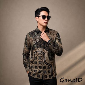 May include: A long-sleeved button-down shirt featuring a complex black and tan geometric batik pattern. The shirt has a standard collar, buttoned cuffs, and a front button placket. The word GonolD is printed in the bottom right corner of the image.