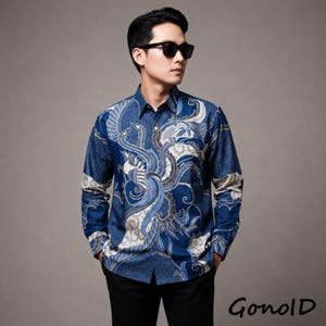 May include: A long-sleeved, button-down shirt with a blue batik pattern featuring a stylized bird design. The shirt has a dark blue base with white and light blue accents. The word "GonolD" is printed in the bottom right corner.