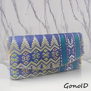 Pode incluir: Uma clutch azul com acabamento dourado e um design estampado. O padrão inclui detalhes dourados, verdes, vermelhos e brancos. A clutch tem formato retangular com aba.