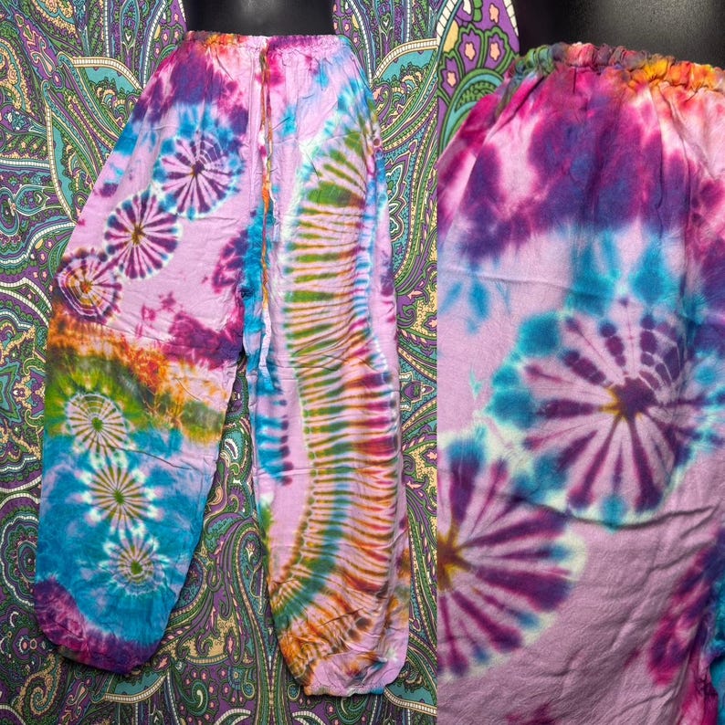 May include: Tie-dye pants in shades of pink, blue, green, and orange. The pants feature a drawstring waist and a relaxed fit. The tie-dye pattern includes spiral and vertical designs, creating a vibrant and colorful look. The pants are made of a soft, lightweight fabric.