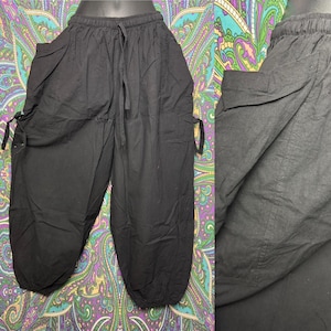 May include: Black cotton pants with a drawstring waist and side ties. The pants have a loose, flowing fit.
