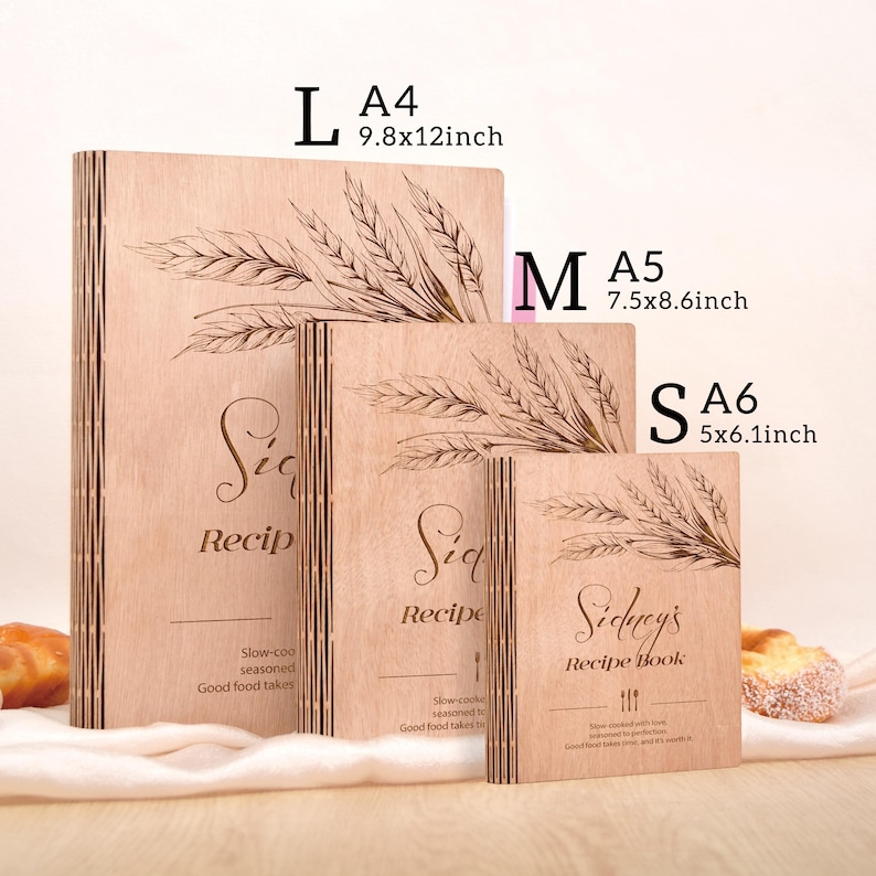 K&ouml;nnte beinhalten: Drei Kochb&uuml;cher aus Holz in den Gr&ouml;&szlig;en L, M und S. Das gr&ouml;&szlig;te ist 25x30cm, das mittlere 19x22cm und das kleinste 13x15cm gro&szlig;. Jedes Buch hat ein Weizen&auml;hren-Design und den Schriftzug "Recipe".