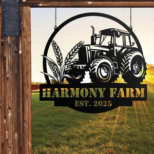 Peut inclure: Panneau métallique noir avec une silhouette de tracteur, des épis de blé et l'inscription « HARMONY FARM EST. 2025 ». Le panneau est suspendu par des chaînes, sur un fond flou.